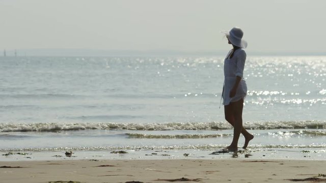 4K Female walks along a beach shore on her own