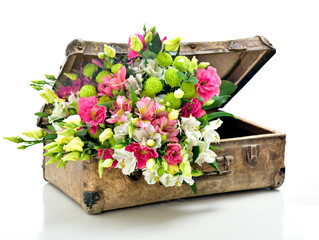 A bunch of beautiful flowers in an old shabby suitcase. Isolated