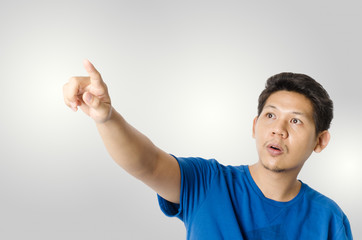 Asia man is pointing to something on blank space,isolated on gray background