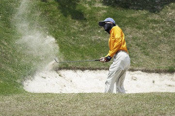 Thai young man golf player in action swing in sand pit during pr