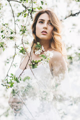 Portrait of beautiful romantic lady in apple trees blossoms