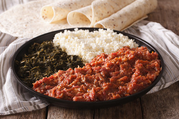 Ethiopian food kitfo: marinated beef with herbs and cheese close-up and injera. horizontal
