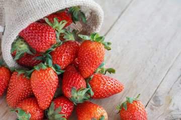 strawberries in small sack on wooden table background