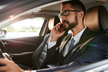 Business executive talking on phone when driving car