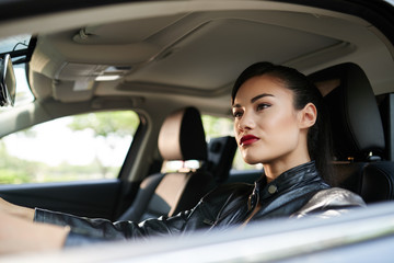 Fototapeta na wymiar Stylish woman in leather jacket driving car