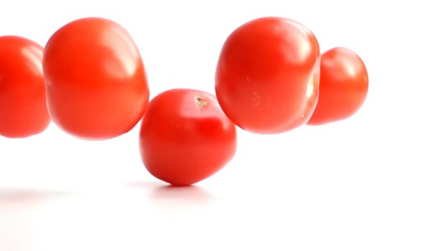 fresh tomatoes falling on white background in slow motion
