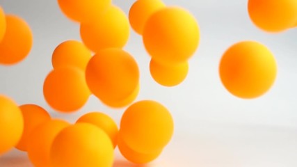 many orange balls falling and bouncing over the white surface slow motion - Powered by Adobe