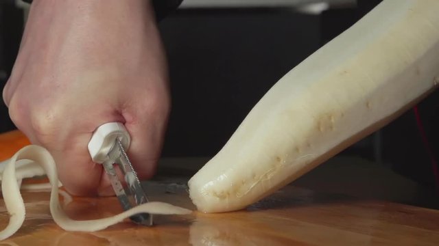 SLOW-CLOSEUP: A cook cleans a daikon on a cutting board in a restaurant kitchen