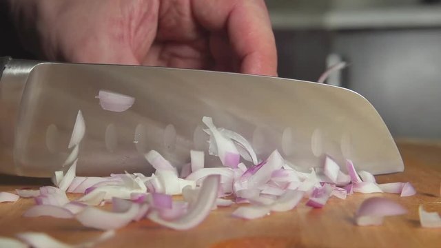 SLOW-CLOSEUP: A cook cuts an onion bulb on on a board