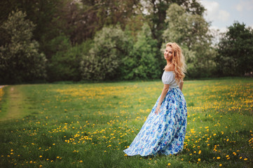 beautiful young woman in floral maxi skirt walking in spring