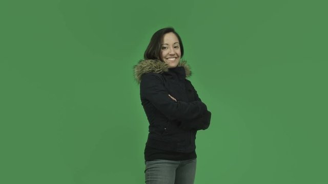 caucasian girl with winter jacket isolated on green screen smiling with arms crossed