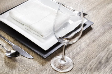 Un plato blanco junto a una copa y cubiertos sobre un mesa de madera. Vista superior y de cerca. Copy space