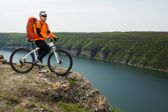 Cyclist in Orange Wear Riding the Bike above River