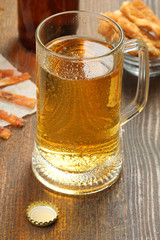 light beer in glass with a variety of sausages in a plate on wooden brown background