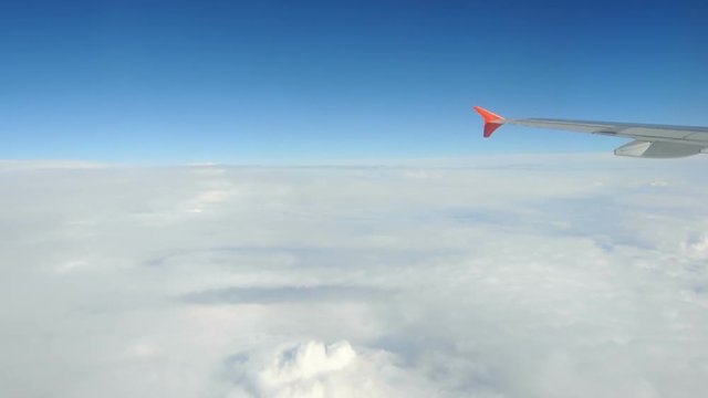 Airplane flying in cumulonimbus cloud, fluffy white clouds view from above, in the sky. Wing aircraft in the atmosphere in the air.