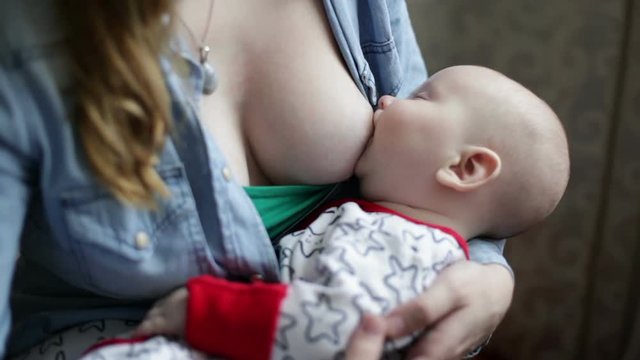 Close-up breast-feeding , baby is sleeping and sucking the breast