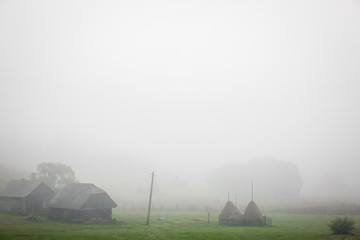 Old houses and haystacks in fog