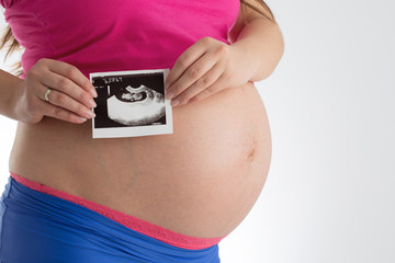 Pregnant woman holding ultrasound scan photo of her baby isolate