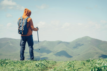 Traveler with trekking poles in mountains