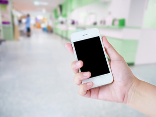 female using smartphone with blur hospital background