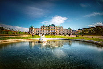 View on Upper Belvedere palace with fontain in Belvedere historic building complex in Vienna. Long exposure technic with blurred clouds and glossy water - obrazy, fototapety, plakaty
