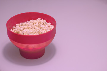 Red bowl of popcorn on a table.