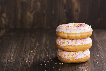 Three fresh sweet donuts over wooden table