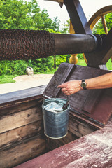 male hand pulls out  bucket of water from well