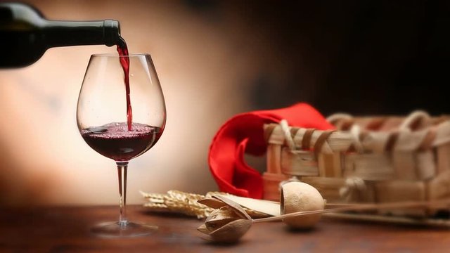 Pouring red wine into baloon wineglass. 