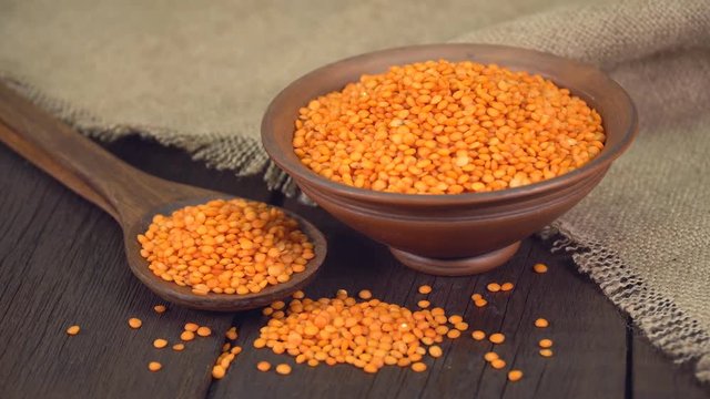 Red lentils in a ceramic bowl on old wooden table ( dolly shot )