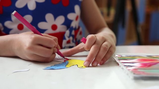 Little girl drawing with markers, she decorates a dove in the kindergarten
