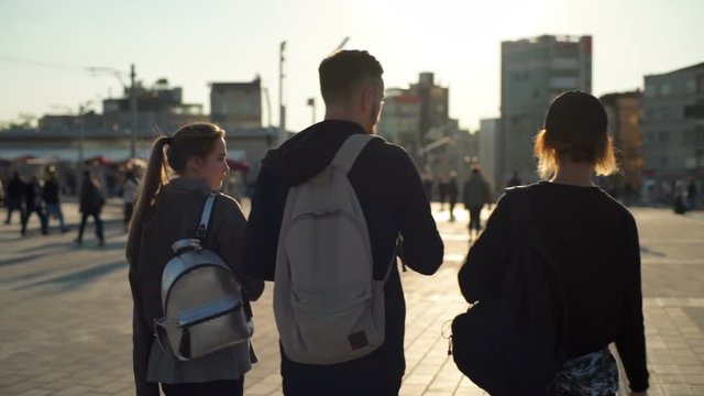 guy between two girls walking on square slow motion