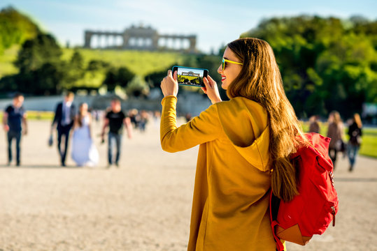 Young female tourist photographing with phone Gloriette building in Schoenbrunn palace in Vienna