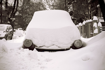 Car stuck in snow on a street with only headlights showing