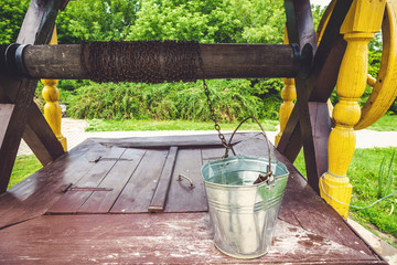 Crouched bucket of water standing on shelf wooden well