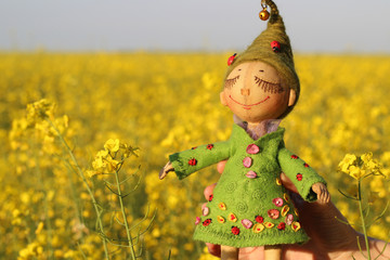 Textile handmade doll toy girl in green dress with green hair with a ladybug in the female hand