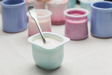 Yogurts assortment  in plastic bowls on light cloth background. Natural and fruit healthy, diet, gourmet dessert for granola breakfast. Sweet yoghurts closeup.