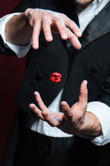 Hands of man magician making red dice flying in air