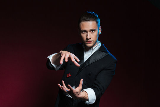 Confident young man magician showing tricks using one flying dice