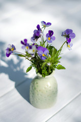 The bouquet of violets on a white table