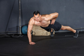 Fototapeta premium Man doing a push-up on one arm in a gym