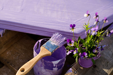 Purple paint in a jar and brush on the background of painted boa