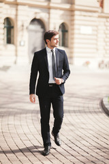 Stylish businessman walking outdoors and looking away