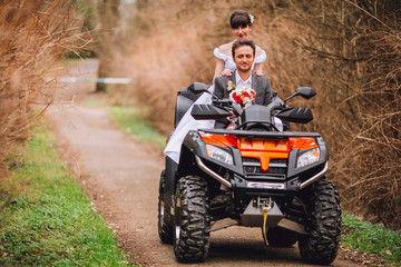 Happy beautiful couple driving four-wheelers ATV on forest road