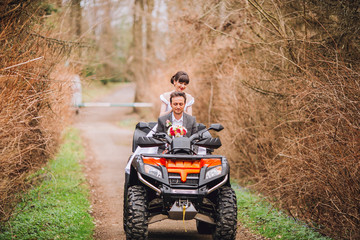 Happy beautiful couple driving four-wheelers ATV on forest road