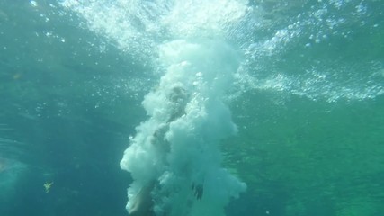 Teenage girl jump and dive into sea water. Underwater Shoot low angle view.
