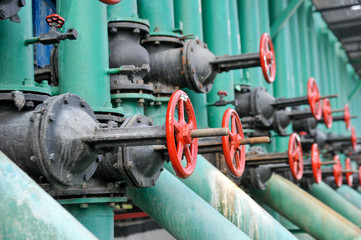 Red faucet with steel pipe in natural gas compressor station in summer day