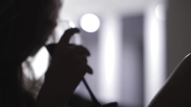 One young attractive woman drinking red wine out of glass in the dark in the apartment. Close up shot. 