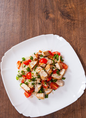 chicken and rice salad with fresh tomatoes in a plate on wooden table