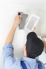 Handwerker öffnet Deckel mit Filter eines Luftschachtes zum Filterwechsel.jpg